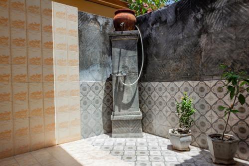 a shower in a bathroom with a potted plant at Hotel O Gunung Mas Homestay in Pemuteran