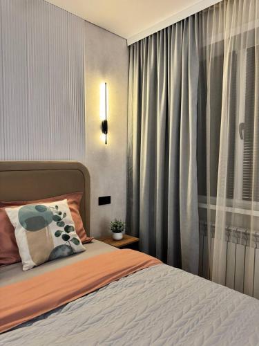 a bedroom with a bed and a window with curtains at Квартира 4-36 in Balqash