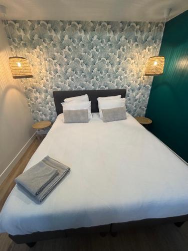 - un grand lit blanc avec 2 oreillers et des serviettes dans l'établissement Le 89 Appartement au calme au centre de Cherbourg, à Cherbourg en Cotentin