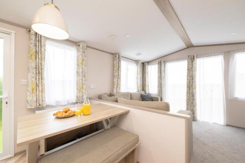 a living room with a table and some windows at Tencreek Holiday Park in Looe