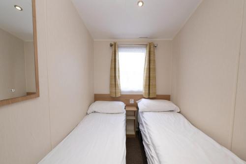 two beds in a small room with a window at Tencreek Holiday Park in Looe