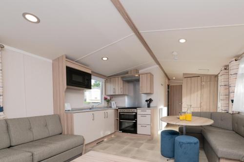 a kitchen and living room with a couch and a table at Tencreek Holiday Park in Looe
