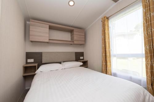 a small bedroom with a bed and a window at Tencreek Holiday Park in Looe
