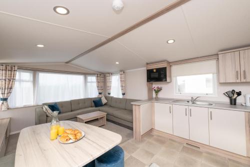 a kitchen and living room with a table and a couch at Tencreek Holiday Park in Looe