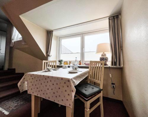 a dining room table with two chairs and a window at Solbeck im Käpitänshaus Andresen in Westerland (Sylt)