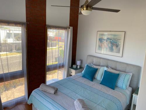 Un dormitorio con una cama con almohadas azules y una ventana. en Garland Grove, en Ocean Grove