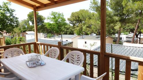 une table et des chaises blanches sur une terrasse en bois dans l'établissement Camping Tikayan Le Méditerranée - Maeva, à Hyères