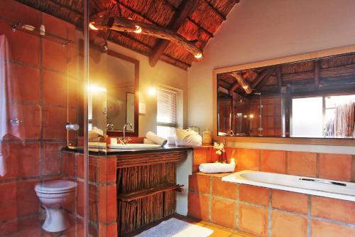 a bathroom with a tub and a toilet and a sink at Itaga Luxury Private Game Lodge in Bela-Bela