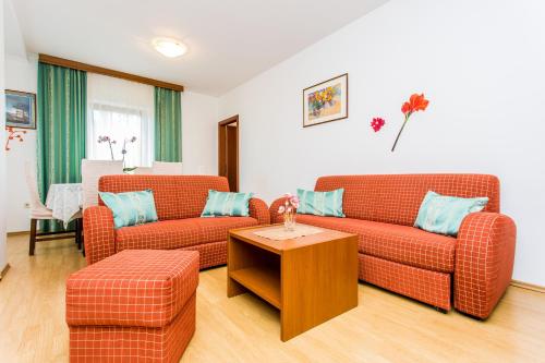 a living room with two orange couches and a table at Guest house Lavanda 2 in Njivice