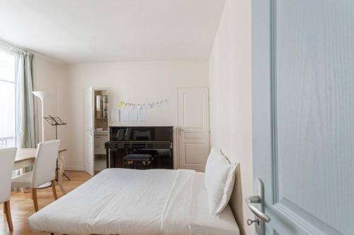 - une chambre blanche avec un lit et un piano dans l'établissement The Azure Pearl -Spacious & Modern, à Paris