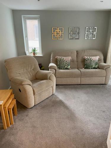 a living room with two couches and a table at Two bedroom apartment set in communal gardens in Verwood