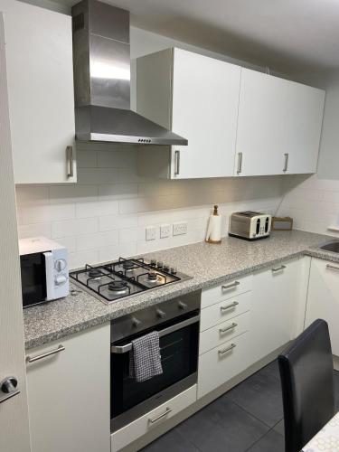 a kitchen with white cabinets and a stove top oven at Two bedroom apartment set in communal gardens in Verwood