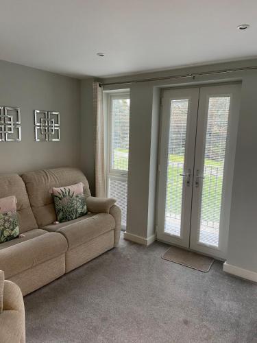 a living room with a couch and sliding glass doors at Two bedroom apartment set in communal gardens in Verwood
