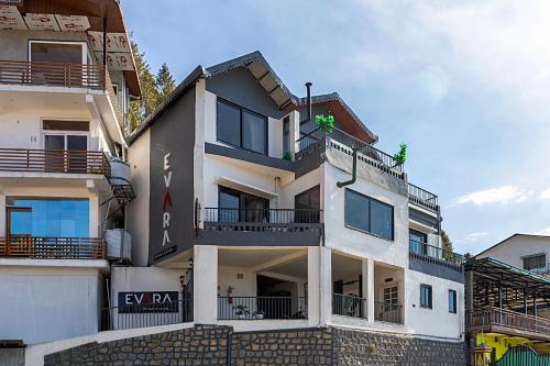 un bâtiment blanc avec des balcons sur le côté dans l'établissement Alaya Stays Evara - 2 BHK Hilltop Hideaway With Balcony, Fireplace & Scenic Views, à Mussoorie