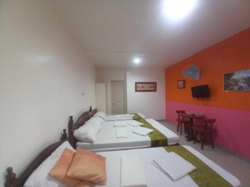 a room with two beds and a table and chairs at Casa Felicisima Inn in Puerto Princesa City