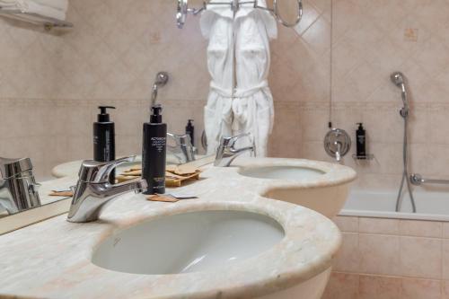 a bathroom with two sinks and a bath tub at Hotel Stendhal in Parma