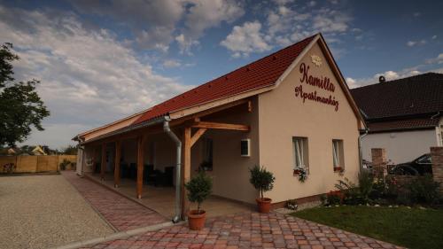 a white building with a red roof and a courtyard at Kamilla Apartmanház Somogyudvarhely OLYANMINTOTTHONCSAKMÉGJOBB in Somogyudvarhely