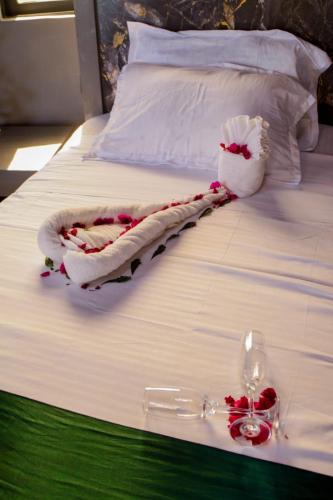 a bed with white sheets and red flowers on it at Amboseli Amanya Lodge in Rift Valley