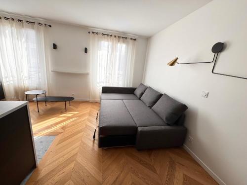 un salon avec un canapé noir dans une pièce dans l'établissement Charme 30min Champs-Elysées, à Clamart