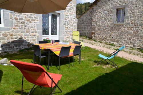 a table with chairs and an umbrella in a yard at Gîte La Maison d'Alphonse 7/8 personnes in Saint-Léger-du-Malzieu