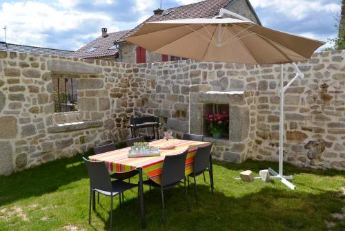 a table and chairs with an umbrella in a yard at Gîte La Maison d'Alphonse 7/8 personnes in Saint-Léger-du-Malzieu