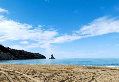 a sandy beach with a rock in the ocean at Siora Angie in Agios Gordios