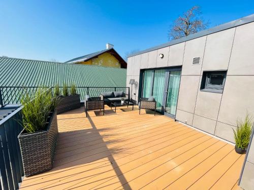 a wooden deck with chairs and a couch on a building at Lai Old Town Apartment with Sauna and Terrace in Tartu
