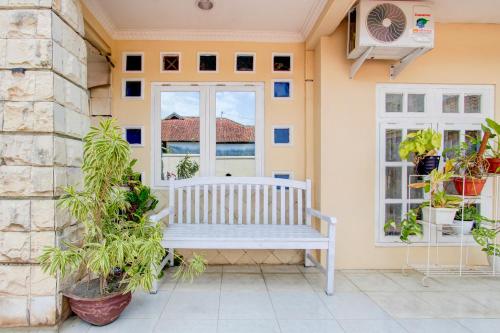 a white bench sitting on the front porch of a house at Hotel O Homestay Ayana Syariah in Yogyakarta