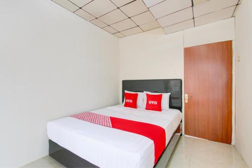 a bedroom with a white bed with red pillows at Hotel O Homestay Ayana Syariah in Yogyakarta