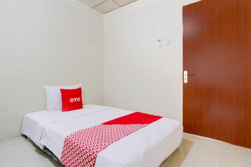 a bedroom with a bed with a red pillow on it at Hotel O Homestay Ayana Syariah in Yogyakarta