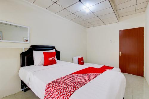 a bedroom with a bed with red and white pillows at Hotel O Homestay Ayana Syariah in Yogyakarta