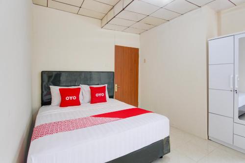 a bedroom with a large bed with two red pillows at Hotel O Homestay Ayana Syariah in Yogyakarta