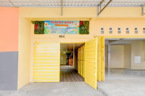 a yellow front door of a building with a sign at Hotel O Alun-Alun Purwokerto Near Gor Satria Purwokerto Formerly Guest House Blessing in Purwokerto
