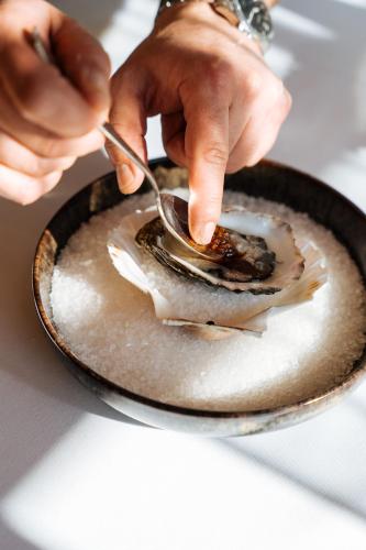 a person eating a oyster on a plate with a spoon at Boutique Hotel Azur in De Haan