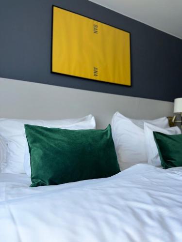 a bed with white sheets and green pillows at Clarion Hotel Grand Östersund in Östersund