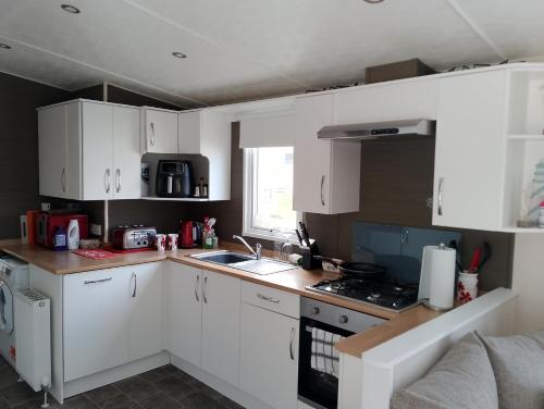 a small kitchen with white cabinets and a sink at 3Bed 2Bath Quiet woodland cul de sac! in Lymington