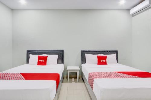 two beds in a room with red pillows at Hotel O D'draman Homestay Syariah in Wanujoyo