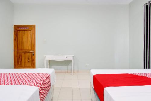 a white room with two beds and a table at Hotel O D'draman Homestay Syariah in Wanujoyo