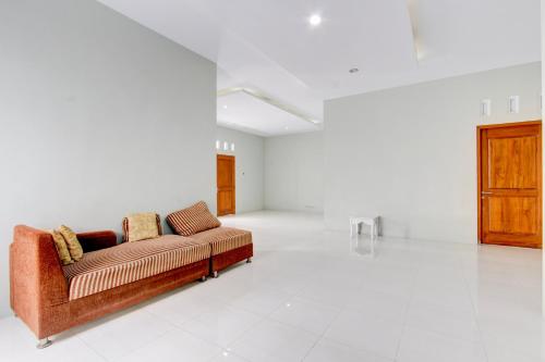 a living room with a couch in a white room at Hotel O D'draman Homestay Syariah in Wanujoyo