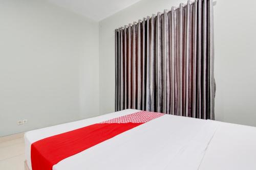 a bedroom with a white bed with a red blanket at Hotel O D'draman Homestay Syariah in Wanujoyo