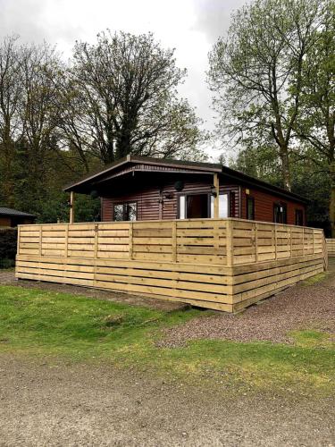 a house with a wooden fence in front of it at The Woodhouse Cabin 8 in Moffat