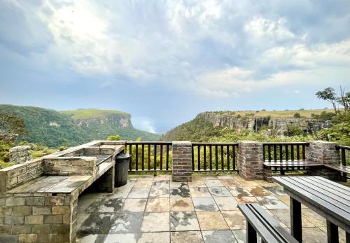 a balcony with benches and a view of the mountains at Panorama Chalets & Rest Camp in Graskop