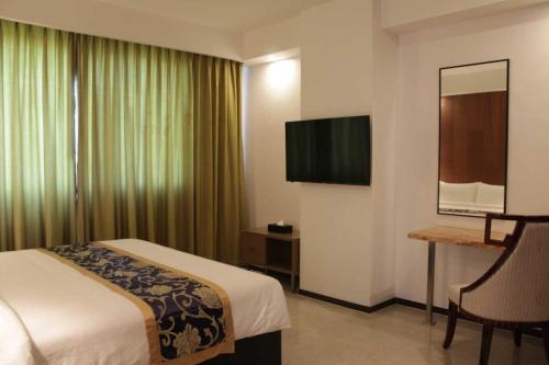 a hotel room with a bed and a flat screen tv at Sunday Hevea Hotel and Resort in Angeles