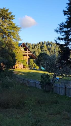 a house in a field with a fence and trees at CHALÉ ESTÂNCIA OURO VERDE in Lages