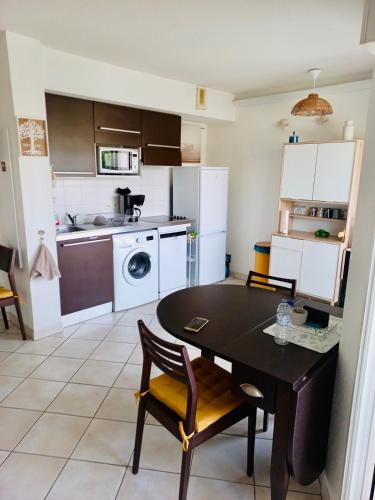 une cuisine avec une table noire et des chaises dans l'établissement Appartement 221 - LES SUITES DE ROBINSON - Résidence avec piscine en bord de Siagne, à Mandelieu-La-Napoule, à Mandelieu-la-Napoule