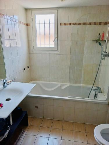 une salle de bain avec une baignoire et un lavabo dans l'établissement Appartement 221 - LES SUITES DE ROBINSON - Résidence avec piscine en bord de Siagne, à Mandelieu-La-Napoule, à Mandelieu-la-Napoule