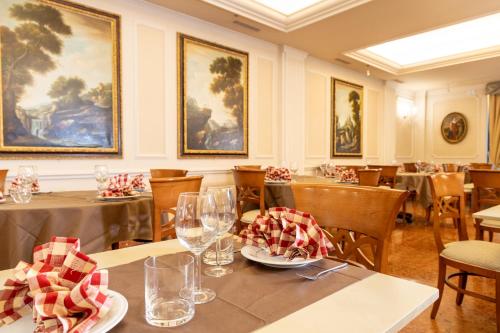 a dining room with tables and chairs and paintings at Hotel Stendhal in Parma