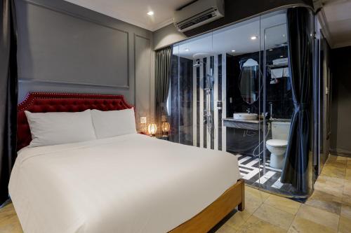 a bedroom with a large white bed and a bathroom at Collection O Le Grand Hanoi hotel - The Sun in Hanoi