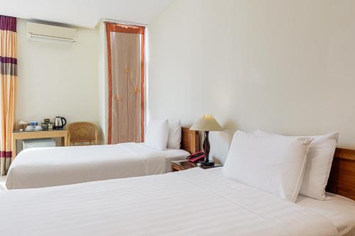 two beds in a hotel room with white sheets at Collection O Le Grand Hanoi hotel - The Sun in Hanoi