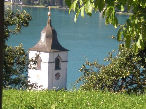 a clock tower on a hill next to a body of water at Auerhiasbauer in St. Wolfgang